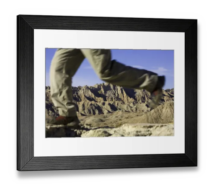 Framed Print : Male hiker walking in badlands, low section (focus on rock formations) Framed Print : Male hiker walking in badlands, low section (focus on rock formations)