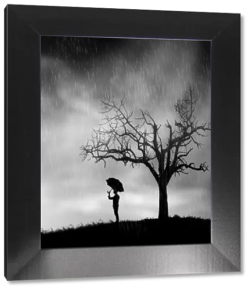 Lonely man with umbrella underneath tree