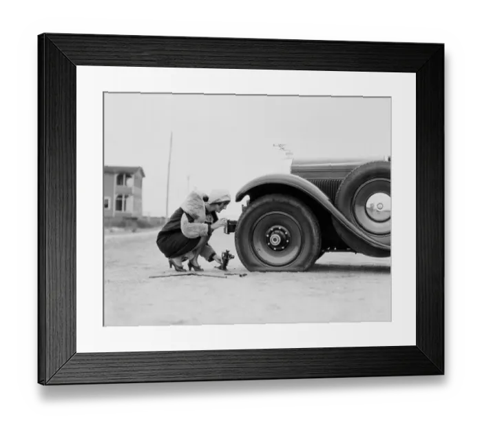 Framed Print : Woman changing flat tire on car Framed Print : Woman changing flat tire on car
