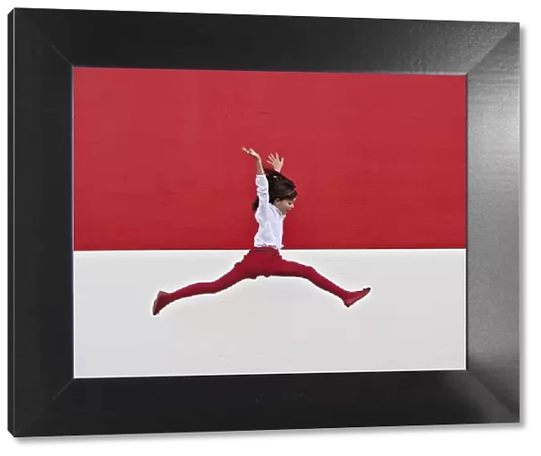 Girl jumping in air at red wall