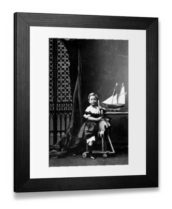 Framed Print : Toy Horse. A young girl sitting on a wooden horse with a toy boat on the desk next to her Framed Print : Toy Horse. A young girl sitting on a wooden horse with a toy boat on the desk next to her