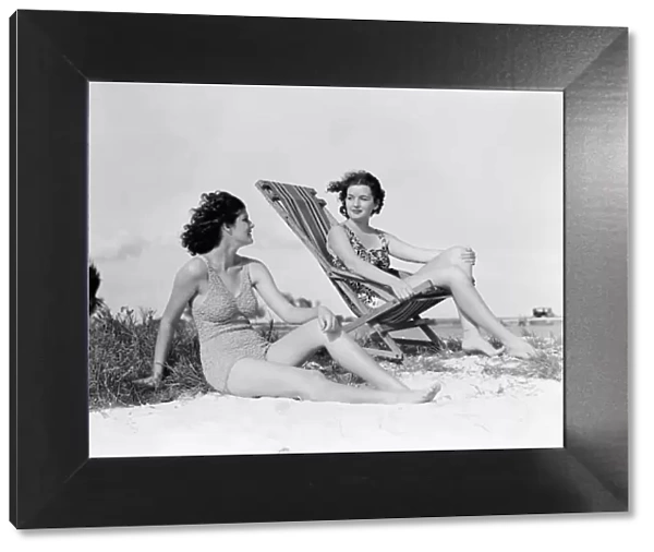Two women in bathing suits on windy beach