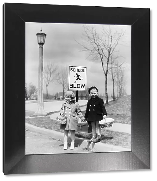 Boy and girl walking to school, about cross street by slow school sign