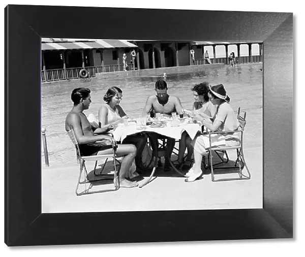 Group of people sitting poolside at hotel, eating dinner, Miami, Florida