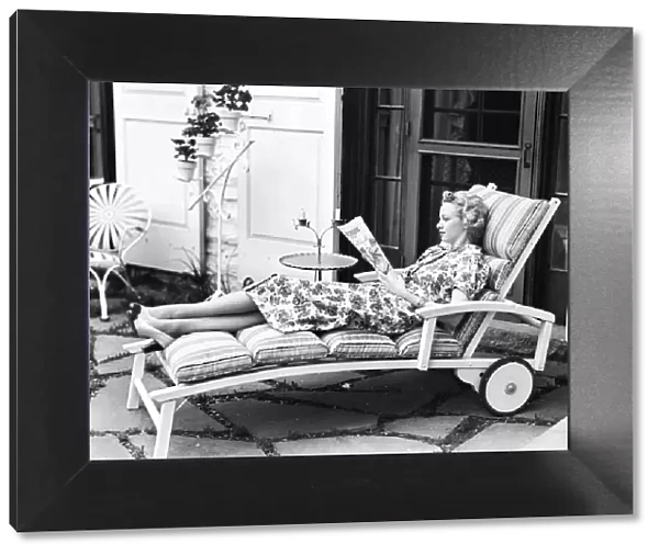 Blonde woman reading magazine on chaise lounge
