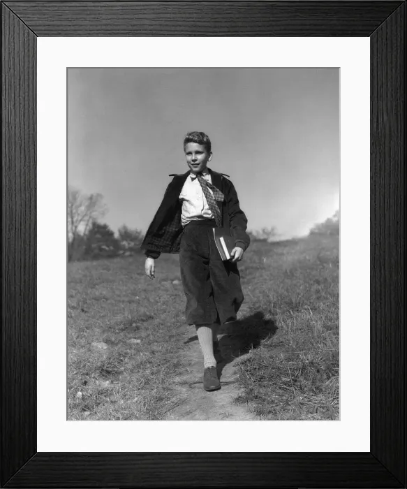 Framed Print : Boy holding books walking along path through meadow, going to school Framed Print : Boy holding books walking along path through meadow, going to school