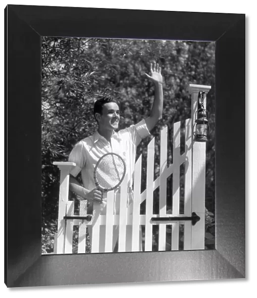 Smiling man in tennis whites, waving