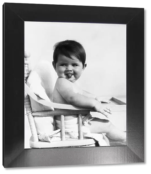 Baby sitting in high chair, sticking out tongue. (Photo by H. Armstrong Roberts  /  Retrofile  /  Getty Images)