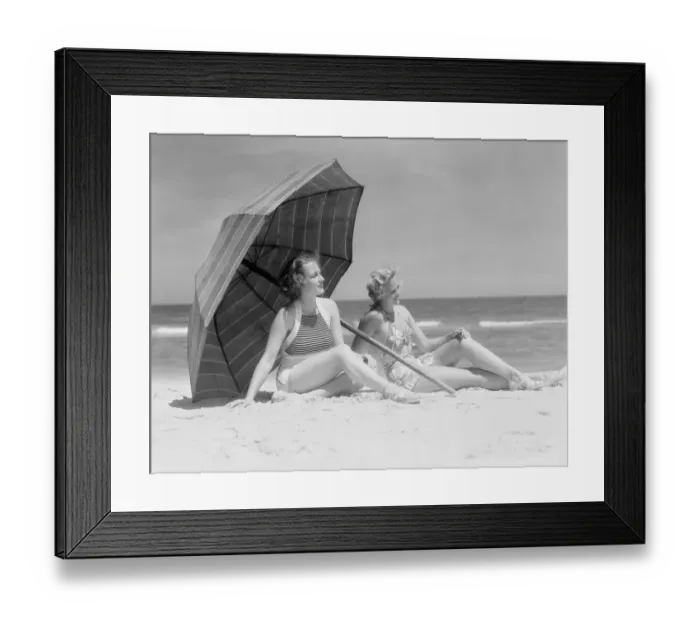 Framed Print : Two women sitting on beach under parasol Framed Print : Two women sitting on beach under parasol