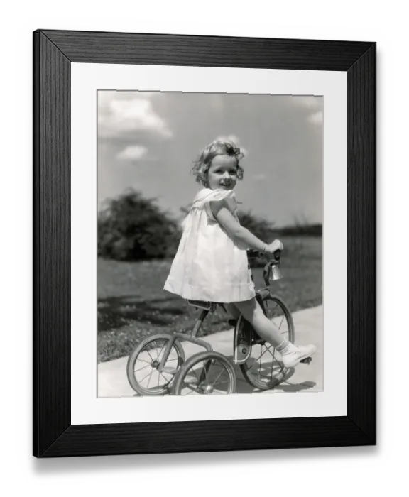 Framed Print : Girl wearing summer dress, riding tricycle down sidewalk. (Photo by H. Armstrong Roberts  /  Retrofile  /  Getty Images)