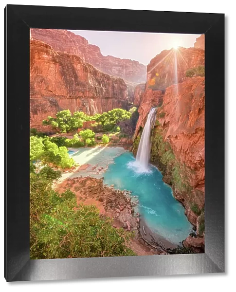 Havasu Falls in Arizona plunges in turquoise waters as the sun rises above the cliffside