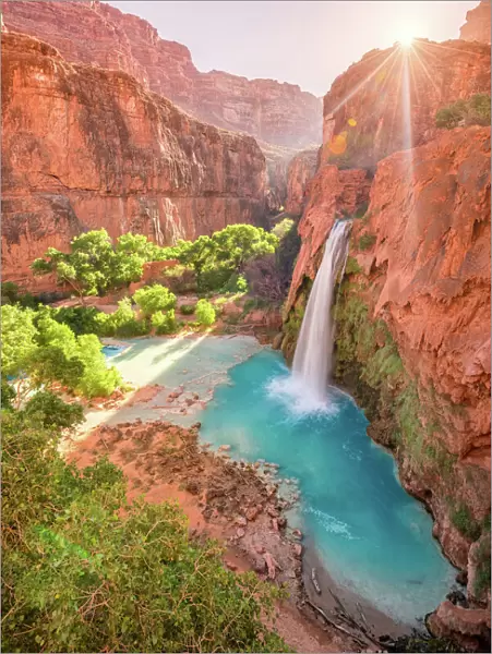 Havasu Falls in Arizona plunges in turquoise waters as the sun rises above the cliffside