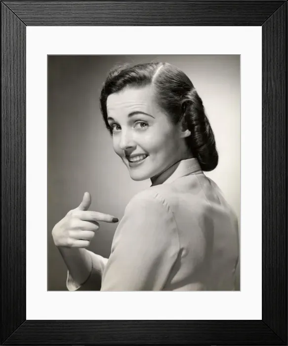 Framed Print : Close-up of smiling woman pointing at herself Framed Print : Close-up of smiling woman pointing at herself