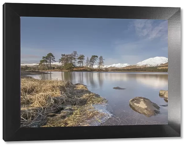 Loch Tula. Scottish Loch with rocks and trees with snowy mountains