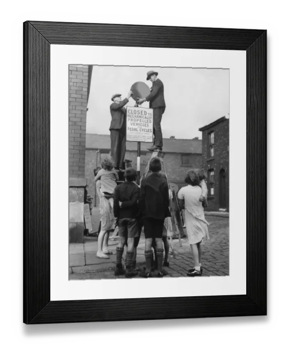 Framed Print : Play Safe. Children watch men putting up a sign closing their street to traffic Framed Print : Play Safe. Children watch men putting up a sign closing their street to traffic