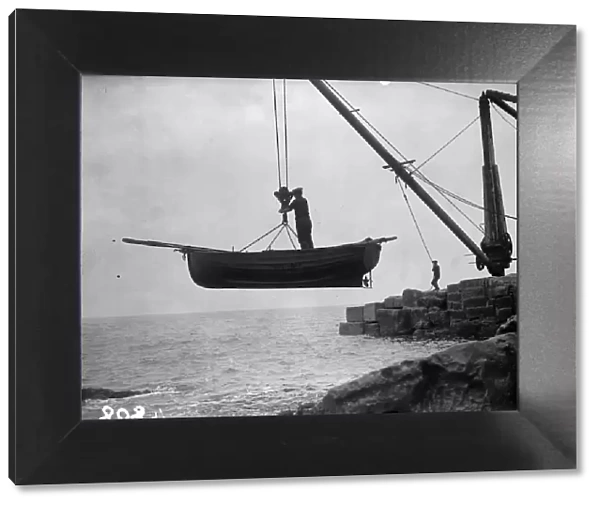 Boat Lift. Portland fishermen lifting their boat over a rocky shore by crane and winch
