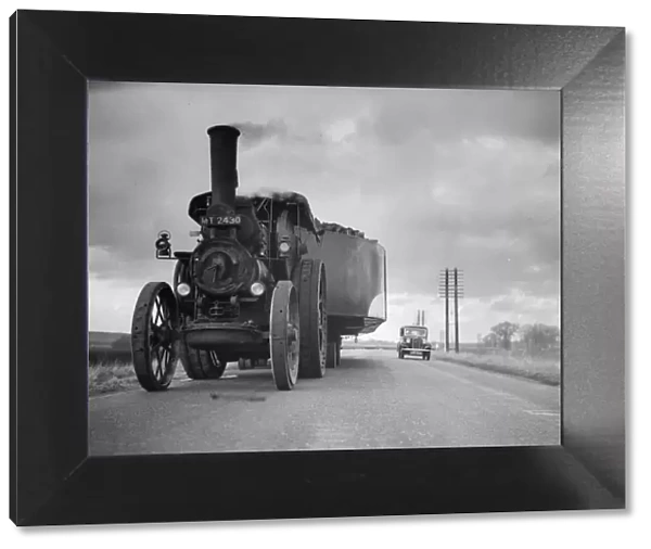 By Road. February 1936: A traction engine pulling an all metal barge on the road to London