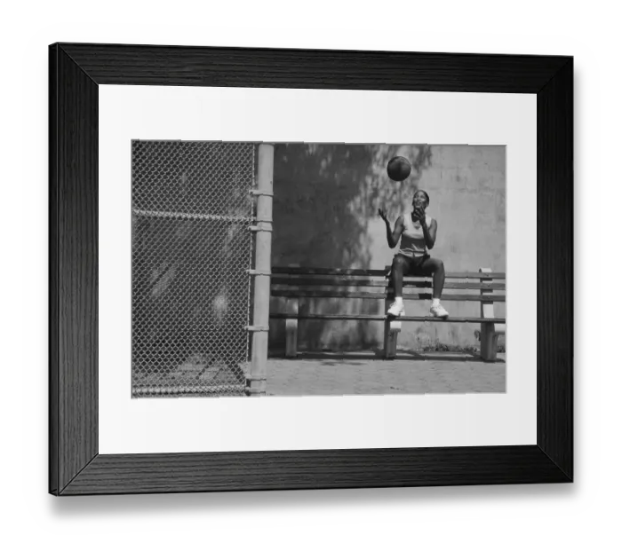 Framed Print : Woman sitting on bench tossing basketball in air (B&W) Framed Print : Woman sitting on bench tossing basketball in air (B&W)