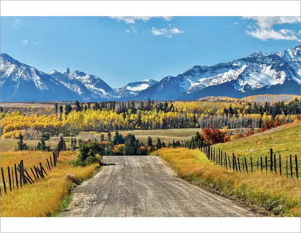 Fence and dirt road leading to San Juan Mountain Range, Ridgway, Colorado, USA