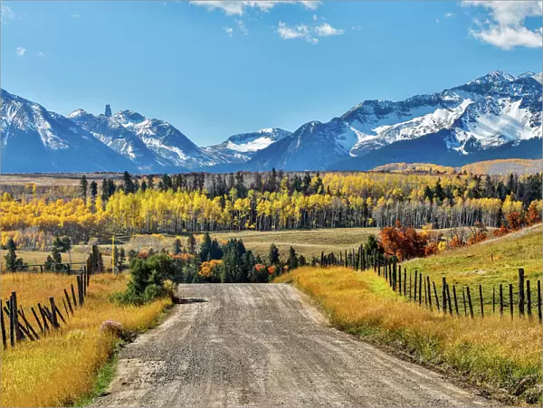 Fence and dirt road leading to San Juan Mountain Range, Ridgway, Colorado, USA