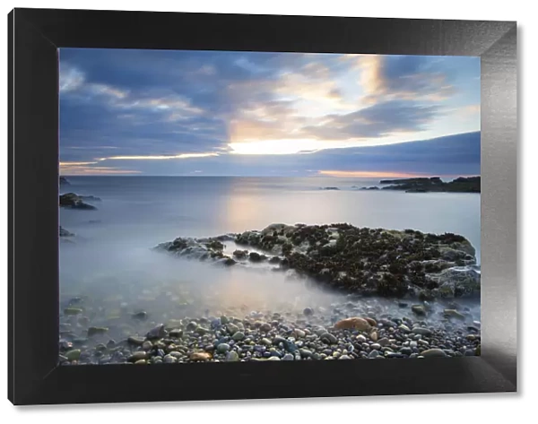 Early morning landscape of ocean over rocky shore with glowing sunrise - Findochty, Scotland