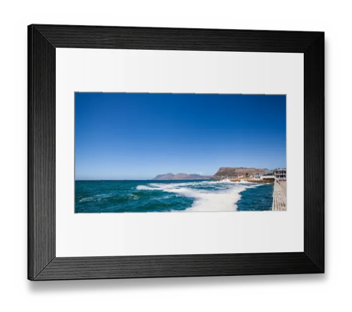 Framed Print : Kalk Bay is a fishing village on the coast of False Bay, South Africa and is now a suburb of greater Cape Town. It lies between the ocean and sharply rising mountainous heights that are buttressed by Framed Print : Kalk Bay is a fishing village on the coast of False Bay, South Africa and is now a suburb of greater Cape Town. It lies between the ocean and sharply rising mountainous heights that are buttressed by