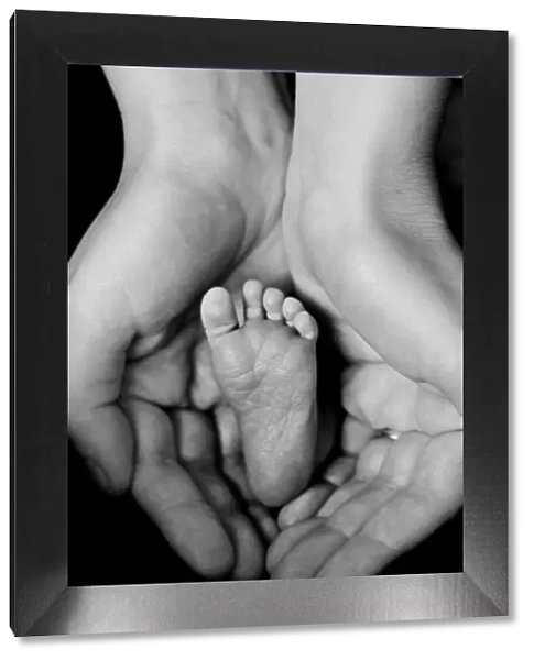 Mothers hands cradling babys foot