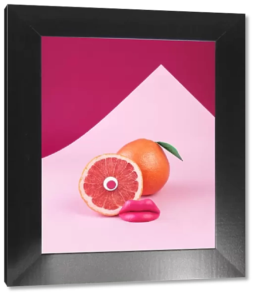 Surreal pink grapefruit with eye and lips on pink background