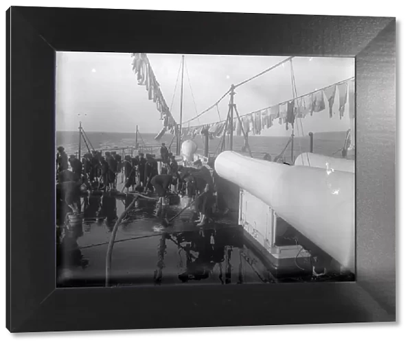 Shipshape. circa 1897: Sailors scrubbing the decks of their sailing ship