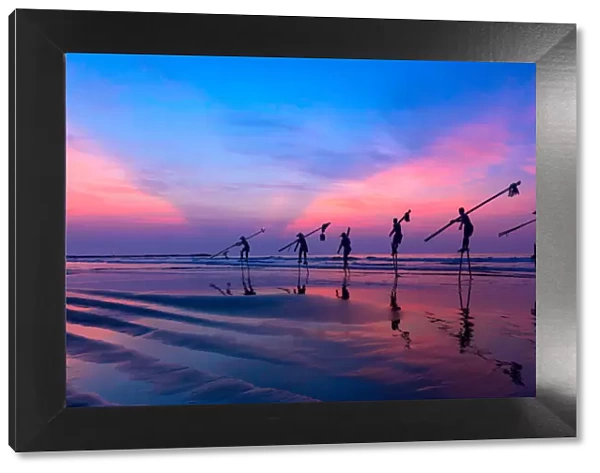 Vietnam - Fishermen going with stilts, hanging fishing tools on the beach, in sunrise