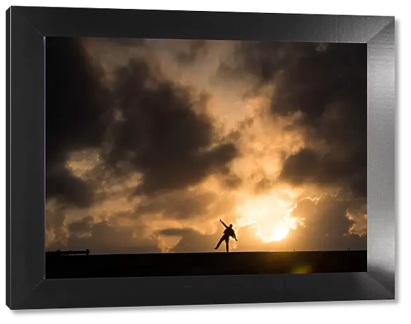 One man standing in causeway over cloudy sunset