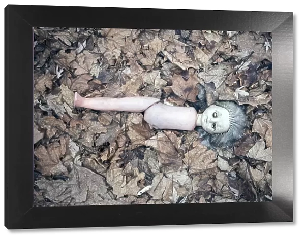 Broken doll lying in the front garden of an abandoned kindergarten, village in the