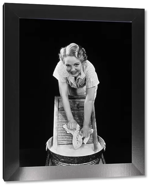 WOMAN CLEANING CLOTHES WITH WASHBOARD