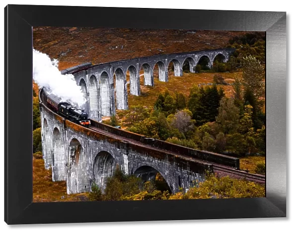 Steam train crossing the Glenfinnan bridge with autumn colors in Scotland