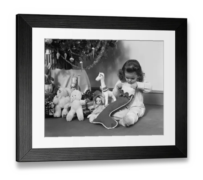 Framed Print : Young girl in pajamas, opening Christmas stocking next to Christmas tree. (Photo by H Framed Print : Young girl in pajamas, opening Christmas stocking next to Christmas tree. (Photo by H