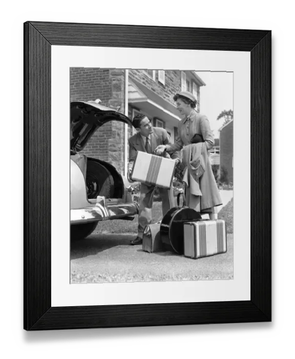 Framed Print : Smiling couple load suitcases into trunk of sedan Framed Print : Smiling couple load suitcases into trunk of sedan