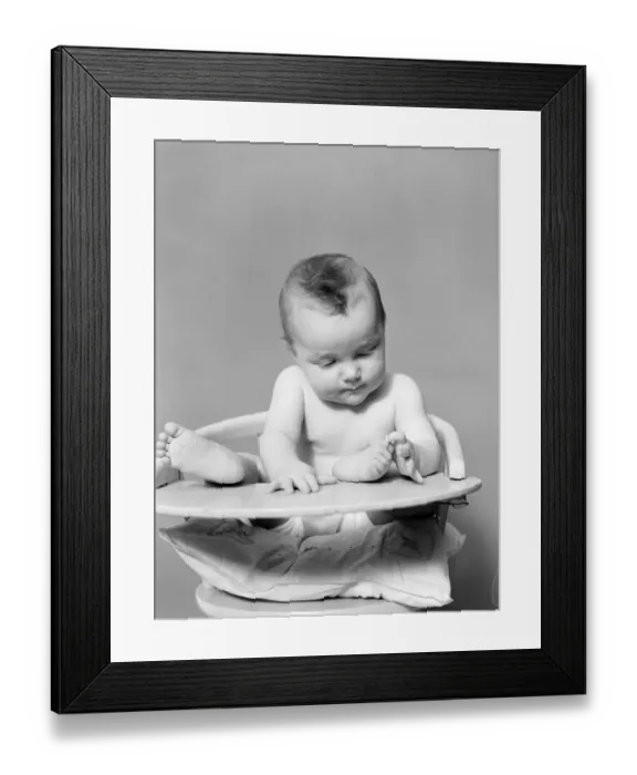 Framed Print : Baby with feet propped up on highchair tray, playing with toes Framed Print : Baby with feet propped up on highchair tray, playing with toes