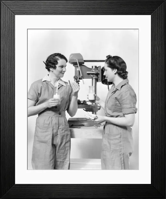 Framed Print : Two women workers standing near drill press, eating sandwich and drinking milk Framed Print : Two women workers standing near drill press, eating sandwich and drinking milk