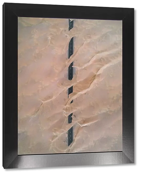Dunes crossing a straight road in the desert, Dubai, United Arab Emirates