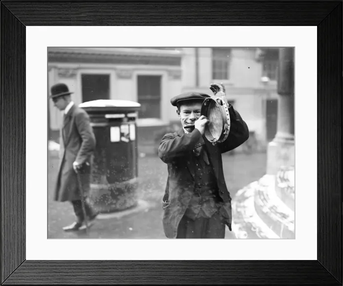 Framed Print : Busker. January 1929: A street musician entertains theatre queues outside a London theatre Framed Print : Busker. January 1929: A street musician entertains theatre queues outside a London theatre