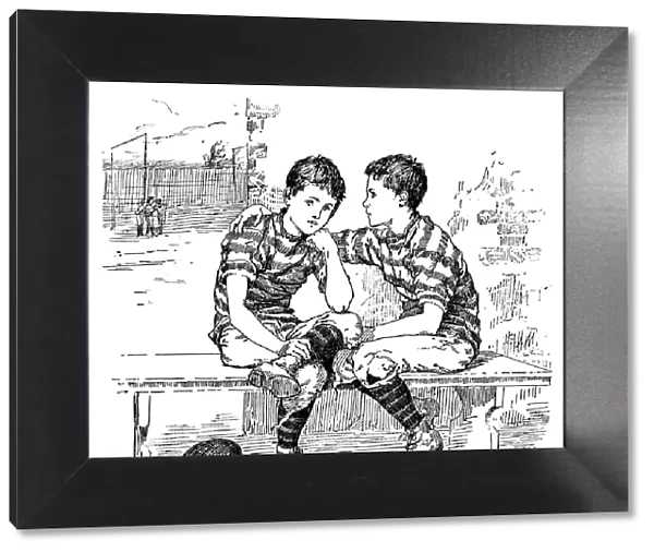 Two Victorian boys in rugby football kit talking on a bench