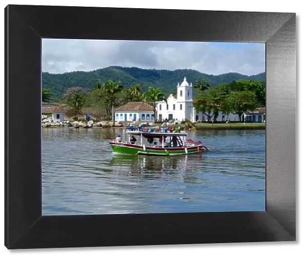 Colourful boat sailing with the pretty Brazilian town Paraty in the back ground