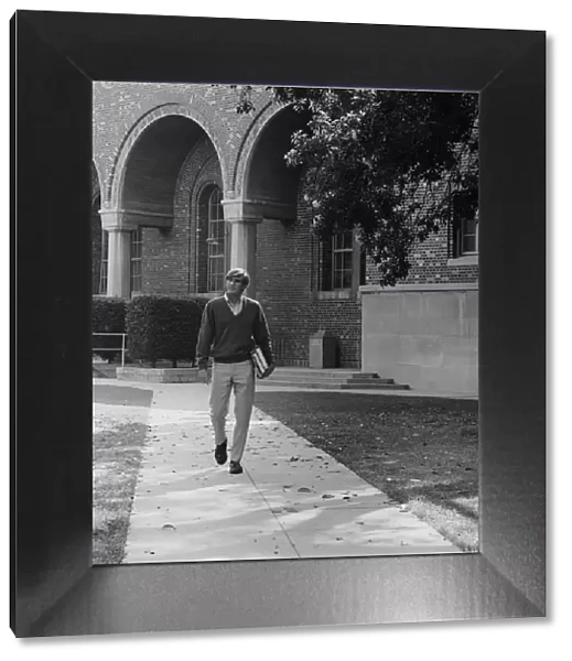 Young man with books walking on campus