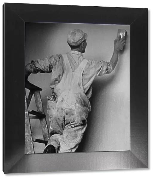 Decorator. A decorator smooths the plaster of a new wall, circa 1950