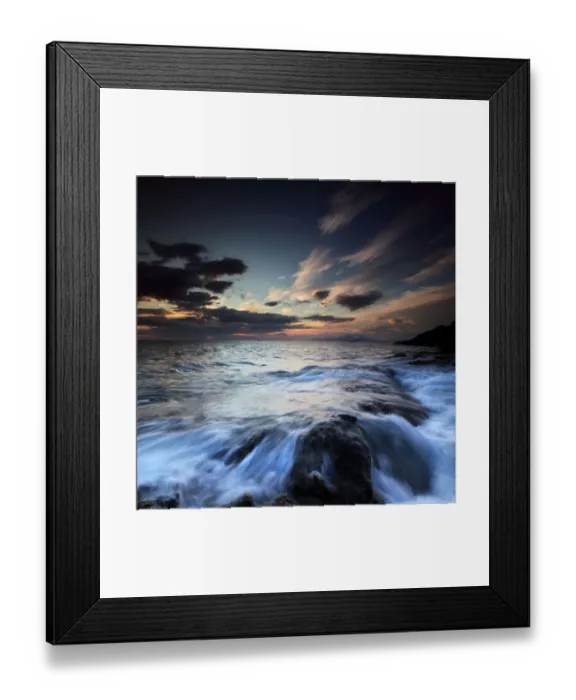 Framed Print : Water flowing over rocks on sea at sunset