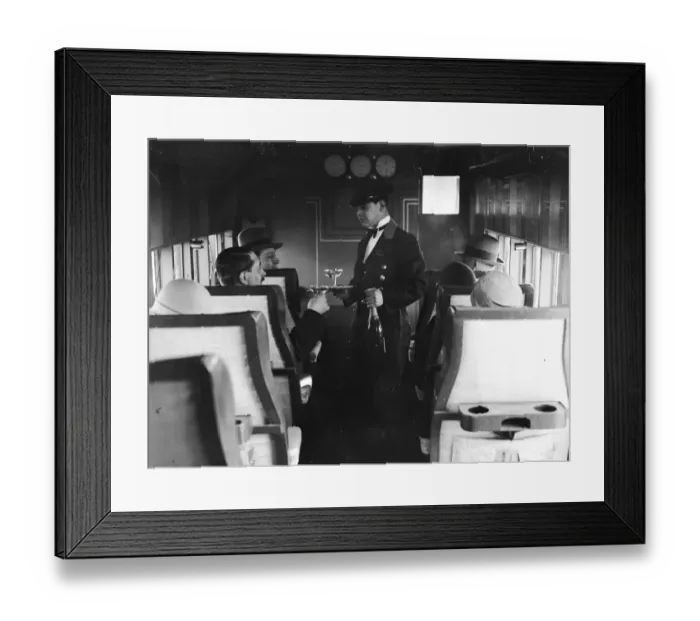 Framed Print : In-Flight. A flight attendant serves drinks to passengers on a French Airliner