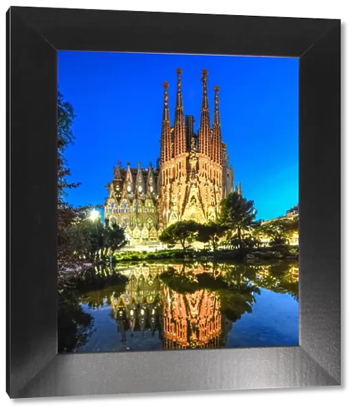 Sagrada Familia illuminated at dusk with reflection on lake in Barcelona, Catalonia