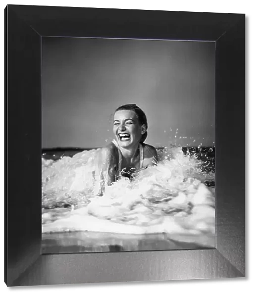 Young woman lying in surf, laughing