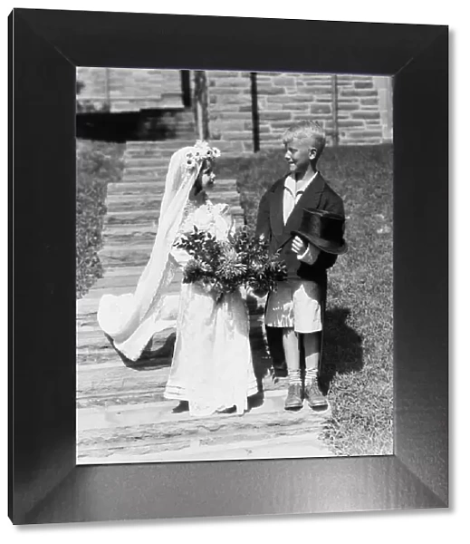 Boy and girl dressed up as bride and groom, outdoors on steps