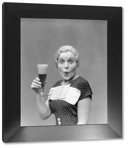 Blonde Woman In Black Dress With Stripes & White Buttons & Trim Holding A Pilsner Glass